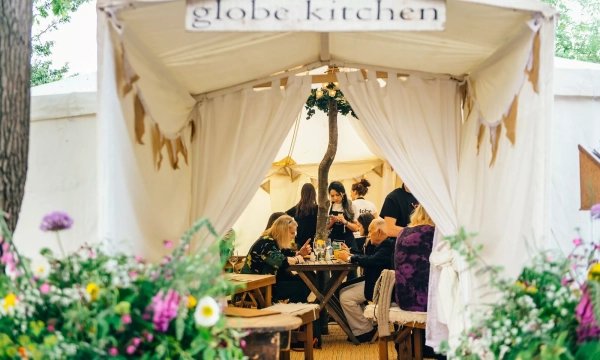 A cozy dining space called "Globe Kitchen" with people seated at a table, surrounded by flowers and rustic decor, creating a welcoming atmosphere.