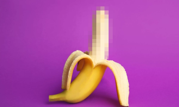 A peeled banana resting on a vibrant purple background, showcasing its yellow skin and curved shape.