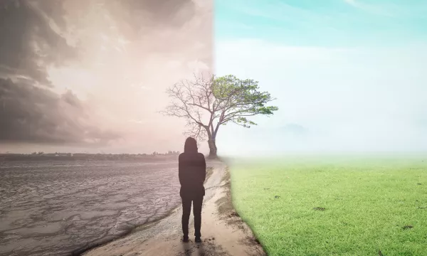 A person stands between two contrasting landscapes: a dry, cracked earth on one side and a lush, green environment on the other, symbolizing climate change and hope.