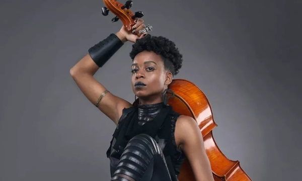 A musician poses confidently with a cello, showcasing a bold fashion style and strong expression, highlighting the fusion of artistry and individuality.