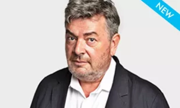 A middle-aged man with gray hair and a beard, wearing a black blazer over a white shirt, looking directly at the camera.