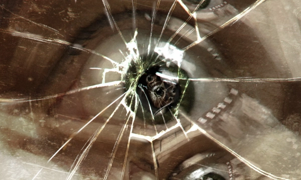 A close-up of a broken mirror reflecting distorted human eyes, suggesting themes of perception and fragmentation.