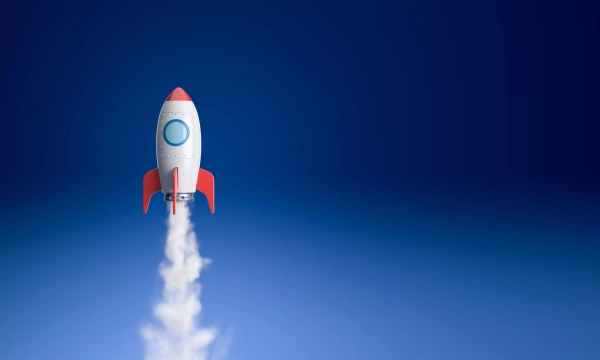 A cartoon-style rocket launching into a clear blue sky, leaving a trail of white smoke behind.