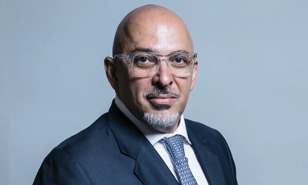 A bald man wearing glasses and a suit poses against a plain background, exuding confidence and professionalism.