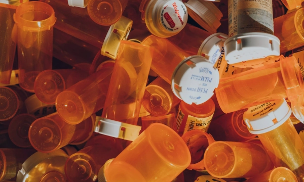 A chaotic arrangement of orange prescription pill bottles scattered across a surface, showcasing various labels and sizes.