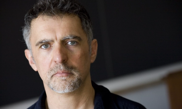Portrait of a middle-aged man with salt-and-pepper hair and a beard, gazing directly at the camera with a serious expression.