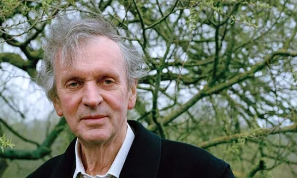 A thoughtful elderly man with grey hair stands outdoors, surrounded by leafless branches, exuding a sense of calm and introspection.