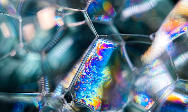 A close-up view of colorful soap bubbles displaying intricate patterns and iridescent hues, showcasing the interplay of light and surface texture.