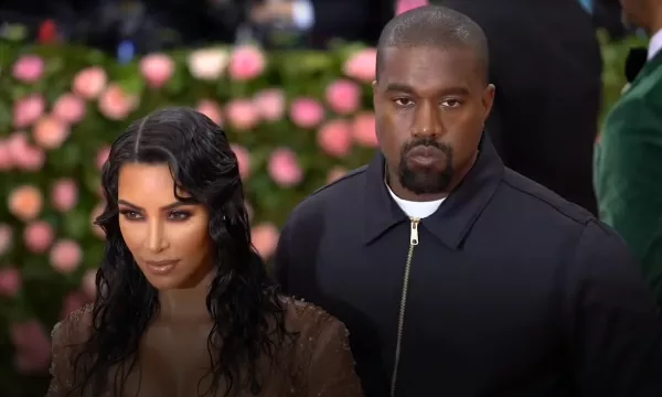 A couple poses together on a red carpet, surrounded by floral decorations, highlighting their glamorous attire.
