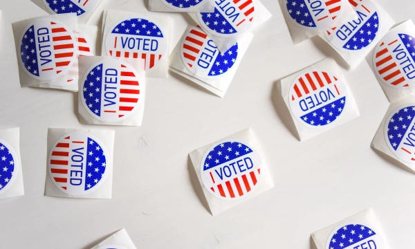 A scattered collection of "I VOTED" stickers featuring red and blue stripes and stars, symbolizing voter participation in elections.