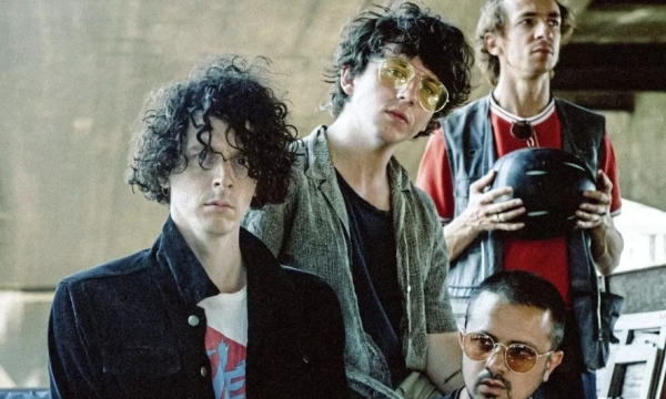 A group of four young men with diverse hairstyles and fashion styles posing together outdoors, showcasing a relaxed and artistic vibe.