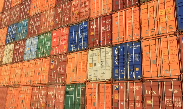 A large, colorful stack of shipping containers in various colors and patterns, showcasing bright oranges, blues, greens, and reds.