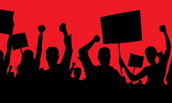 Silhouetted figures of protesters raising their fists and holding signs against a bright red background, symbolizing a rally or demonstration for a cause.
