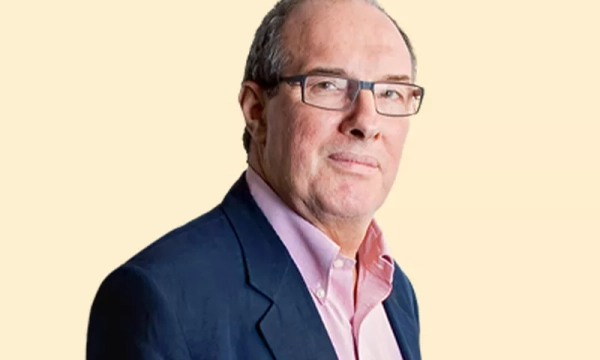 A middle-aged man with glasses wearing a dark blazer over a light shirt, posing against a plain background.