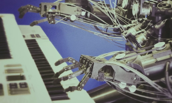 A robotic arm with intricate mechanical fingers plays a keyboard, showcasing advanced engineering and design in robotics and music interaction.