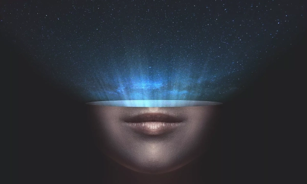 A surreal image depicting a face with an open top, revealing a starry night sky and light rays emanating from within.