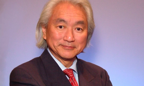 A distinguished Asian man with long silver hair, wearing a black suit and a red tie, poses confidently against a light blue background.