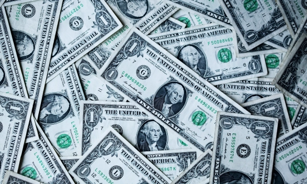 A collection of one-dollar bills arranged haphazardly, showcasing the detailed design and portrait of George Washington.