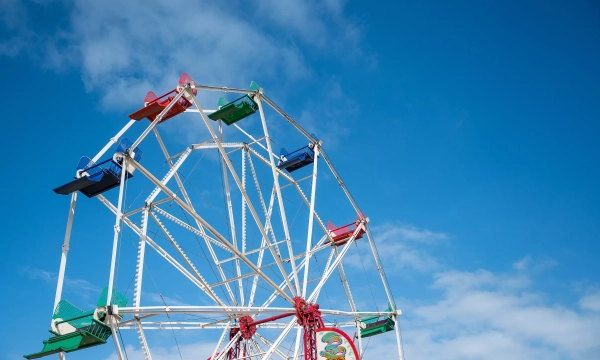 A colorful ferris wheel against a clear blue sky, showcasing its vibrant seats and structure.