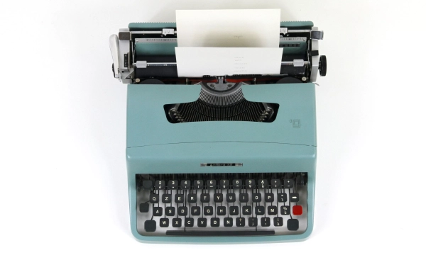 A vintage turquoise typewriter with a sheet of paper partially inserted, showcasing the keys and classic design elements.